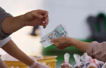 žena předává prodavači české peníze