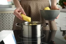 Žena dává brambory do hrnce