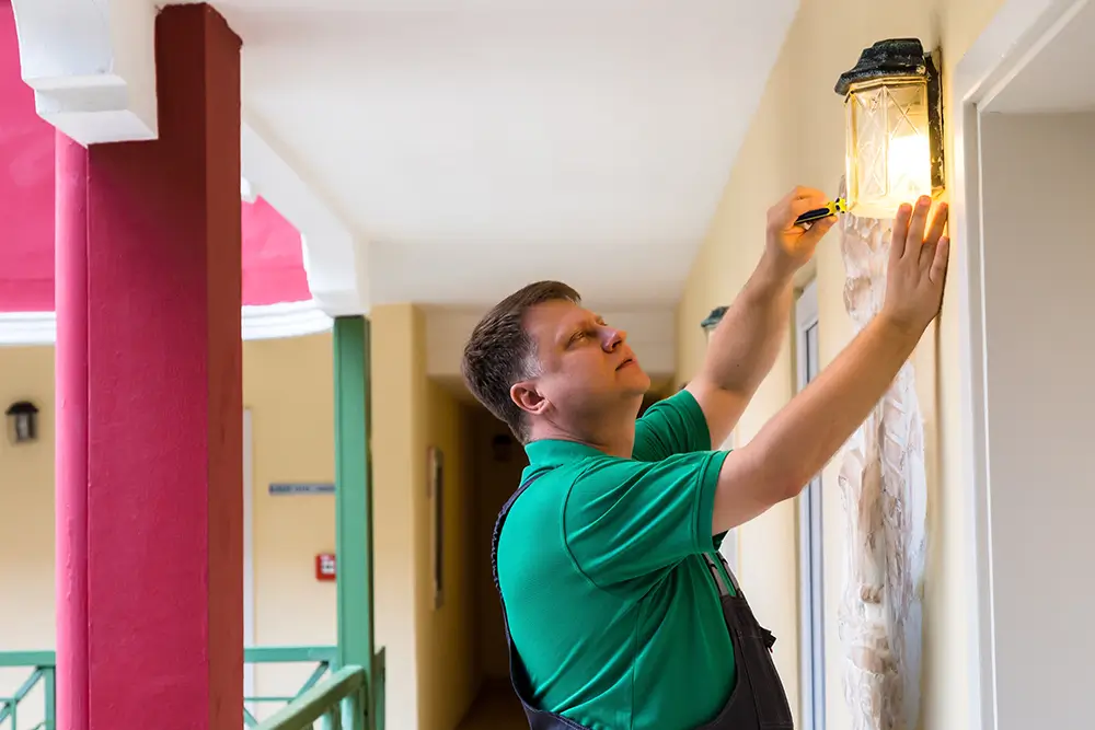 Jako údržbář se budete starat o každodenní údržbu budovy, hotelových pokojů a veřejných prostor. - Techsvět údržbář v hotelu opravuje lampu