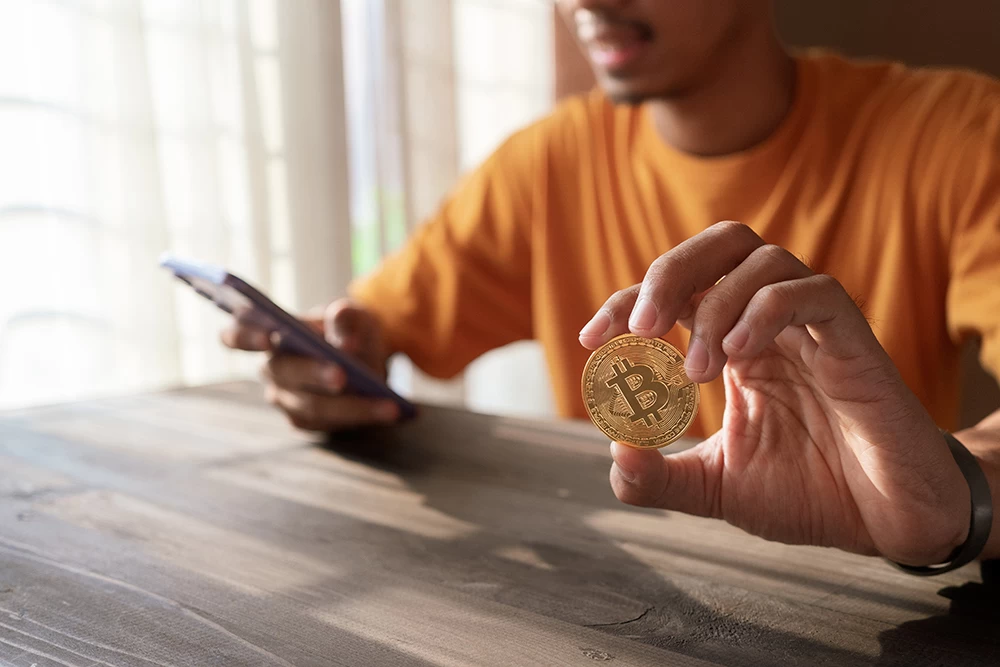 Na stránku podvodníků se dostanete, jakmile kliknete na reklamu. - Techsvět mužb s bitcoinem a telefonem v ruce