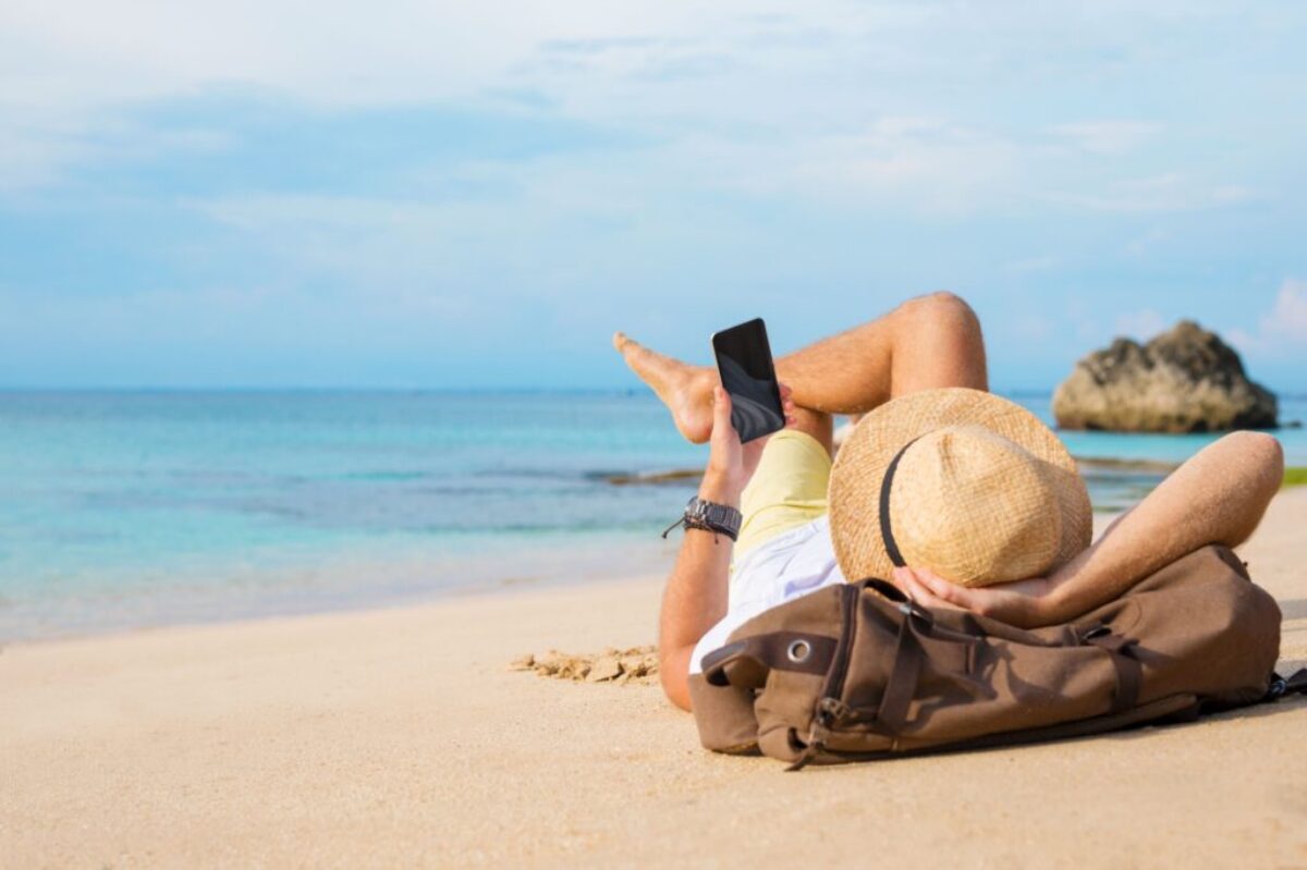 Turista na pláži s telefonem