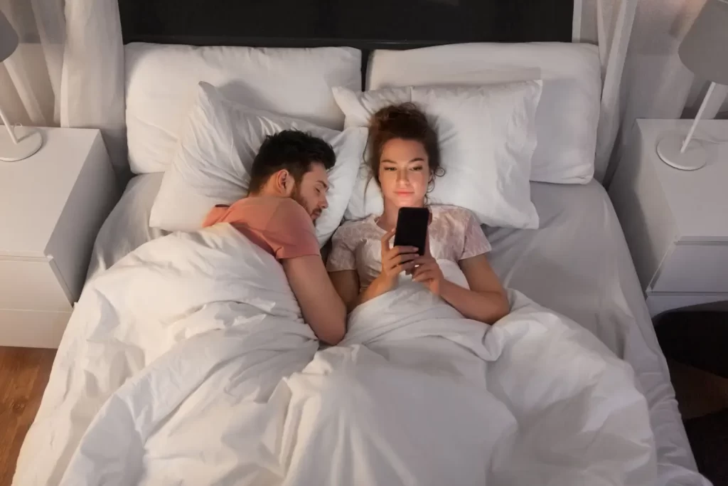 Kozorozi ve vztahu často ulítnou a najdou si bokovku - Techsvět žena píše zprávy na mobilu, vedle ní leží manžel