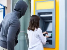 Muž stojí za ženou u bankomatu