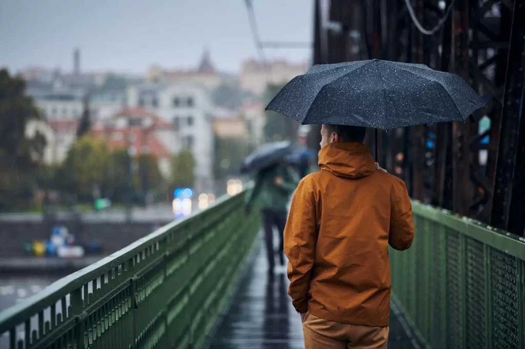 Počasí na druhý květnový státní svátek bude pochmurné, FOTO: Shutterstock - Techsvět muž jde s deštníkem po mostě