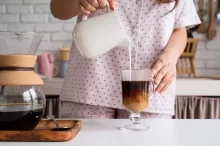 Žena si lije mléko do kávy