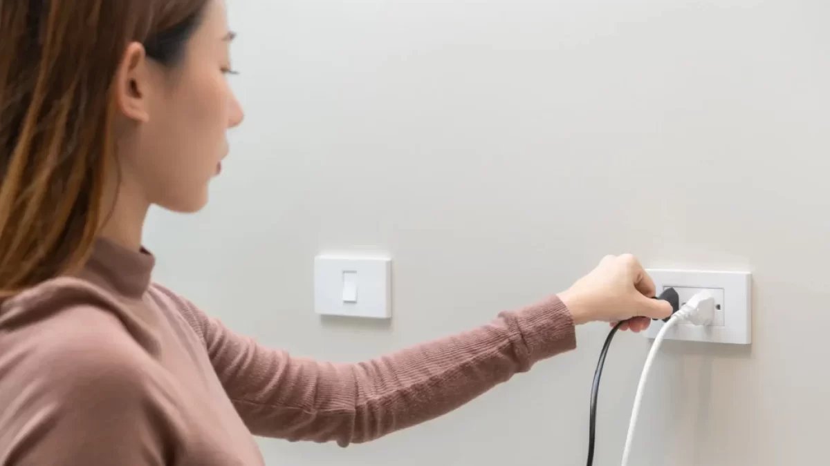 žena vypojuje spotřebič ze zásuvky