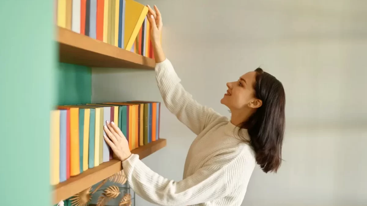 Žena bere knížku z knihovny.
