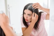 žena prohlíží odrosty v zrcadle
