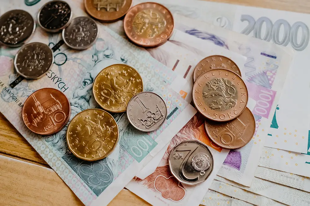 Všechny mince 20 a 50 Kč Petra hází do kasičky. - Techsvět bankovky a mince na stole