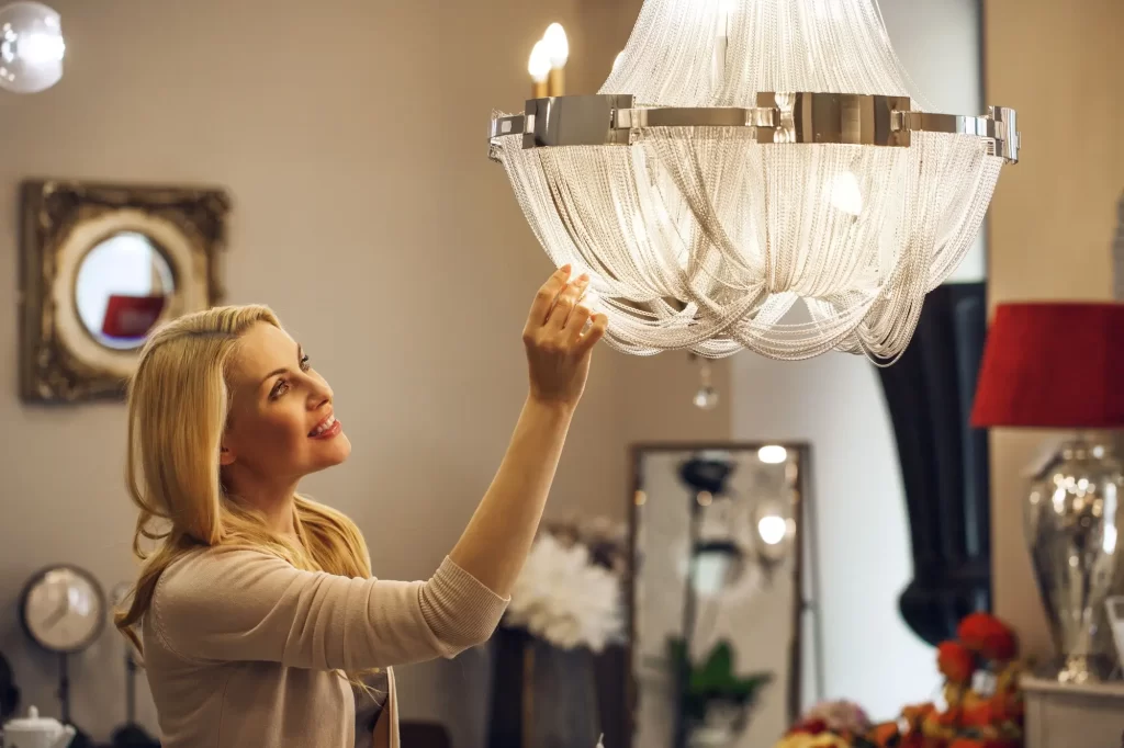 Lustr2 - Techsvět Mladá žena v obývacím pokoji obdivuje křišťálový lustr