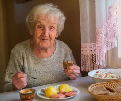 Seniorka sedí u stoly s obědem