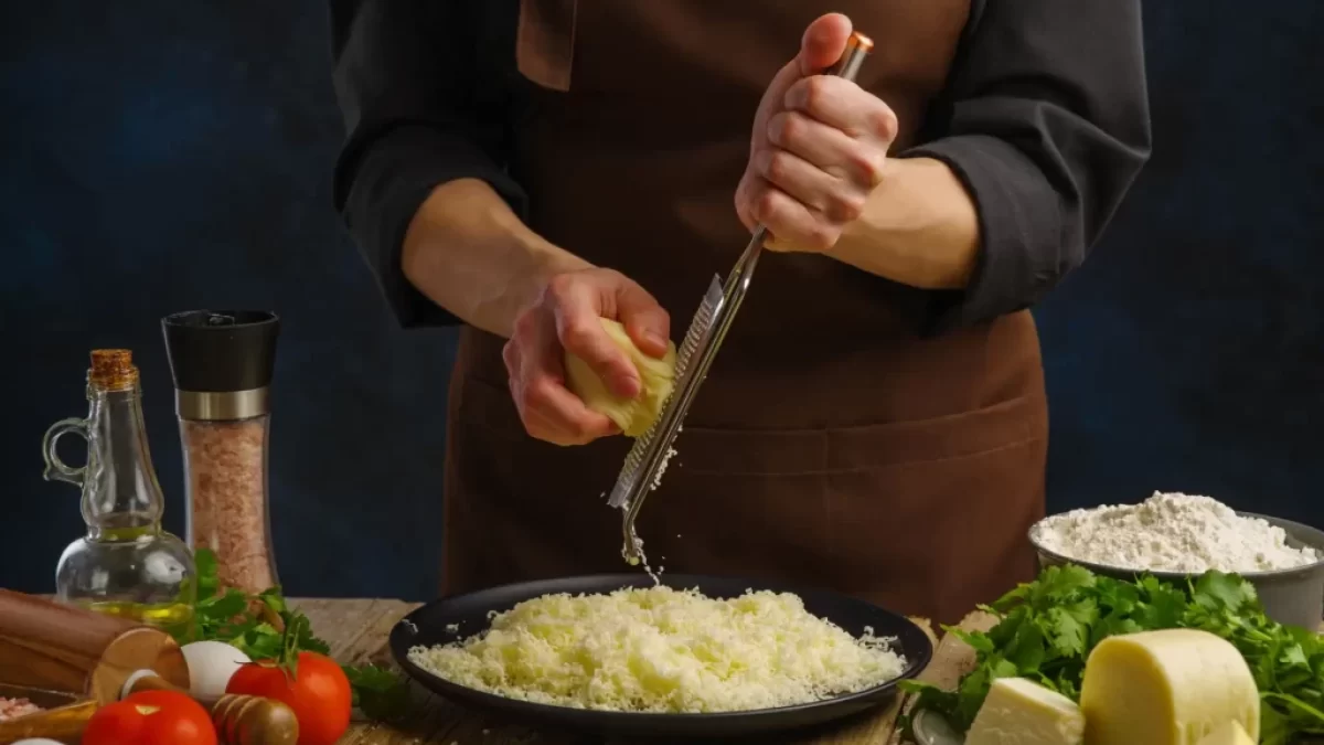 Žena strouhá sýr na ručním struhadle