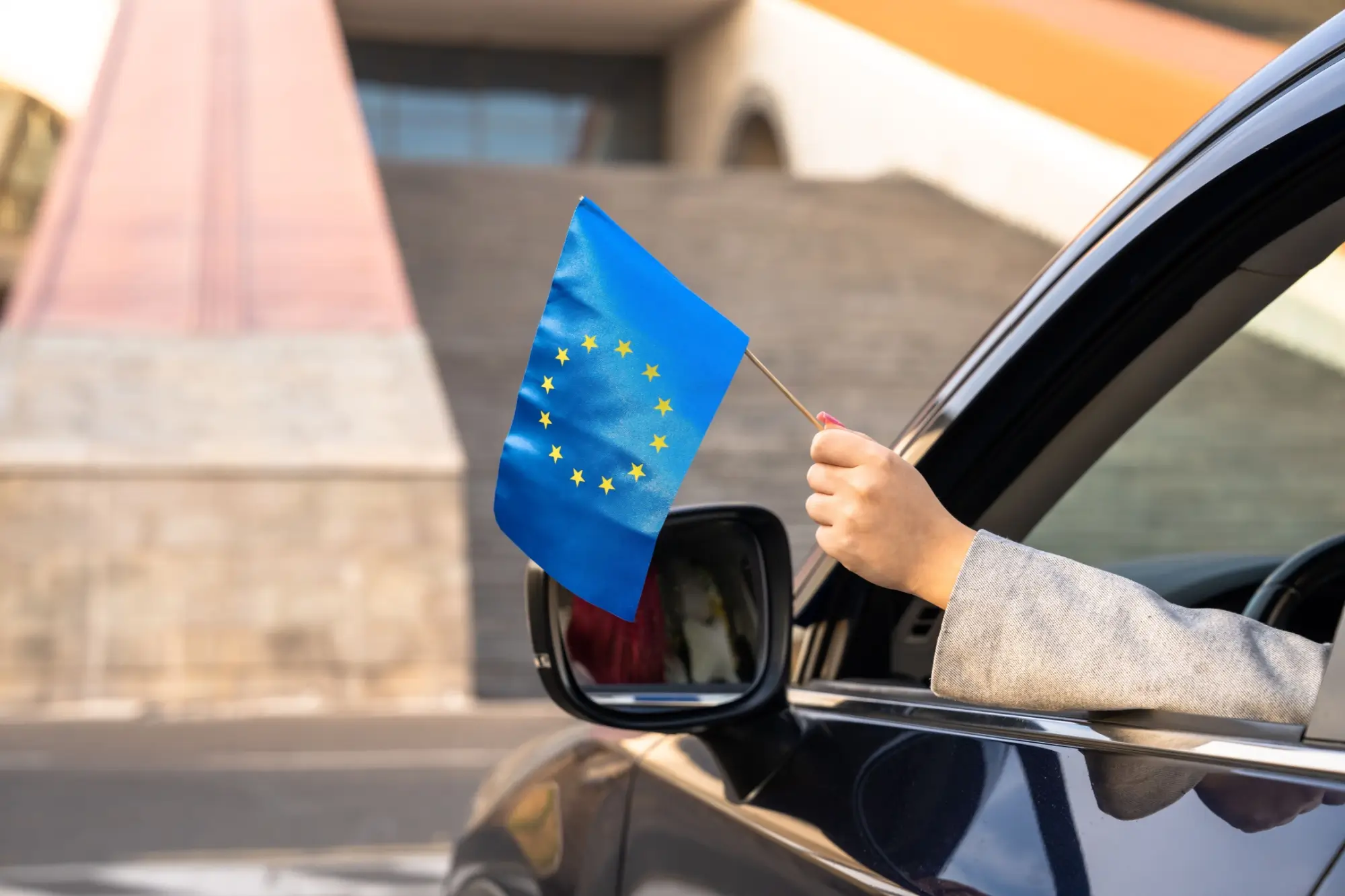 Shutterstock_2549548535 - Techsvět Ruka s vlaječkou EU z auta