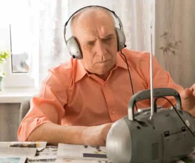Senior se sluchátky poslouchá rádio