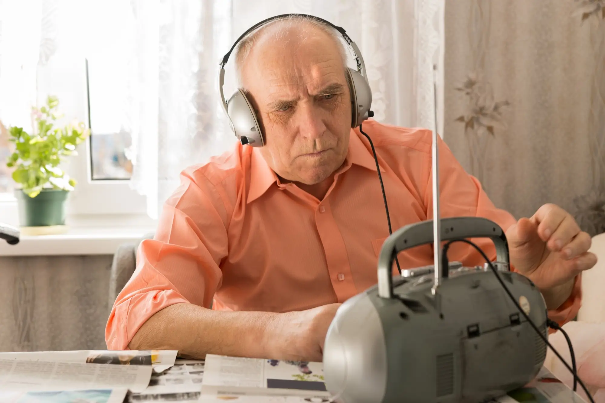 Senior se sluchátky poslouchá rádio