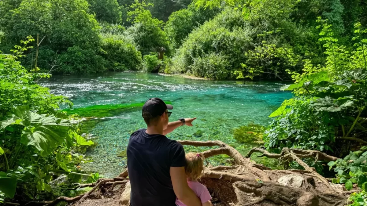 Muž s batoletem sedí na břehu jezírka