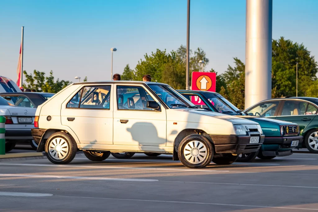 auto3 - Techsvět Auto Škoda Favorit zaparkované na parkovišti mezi dalšími vozy.