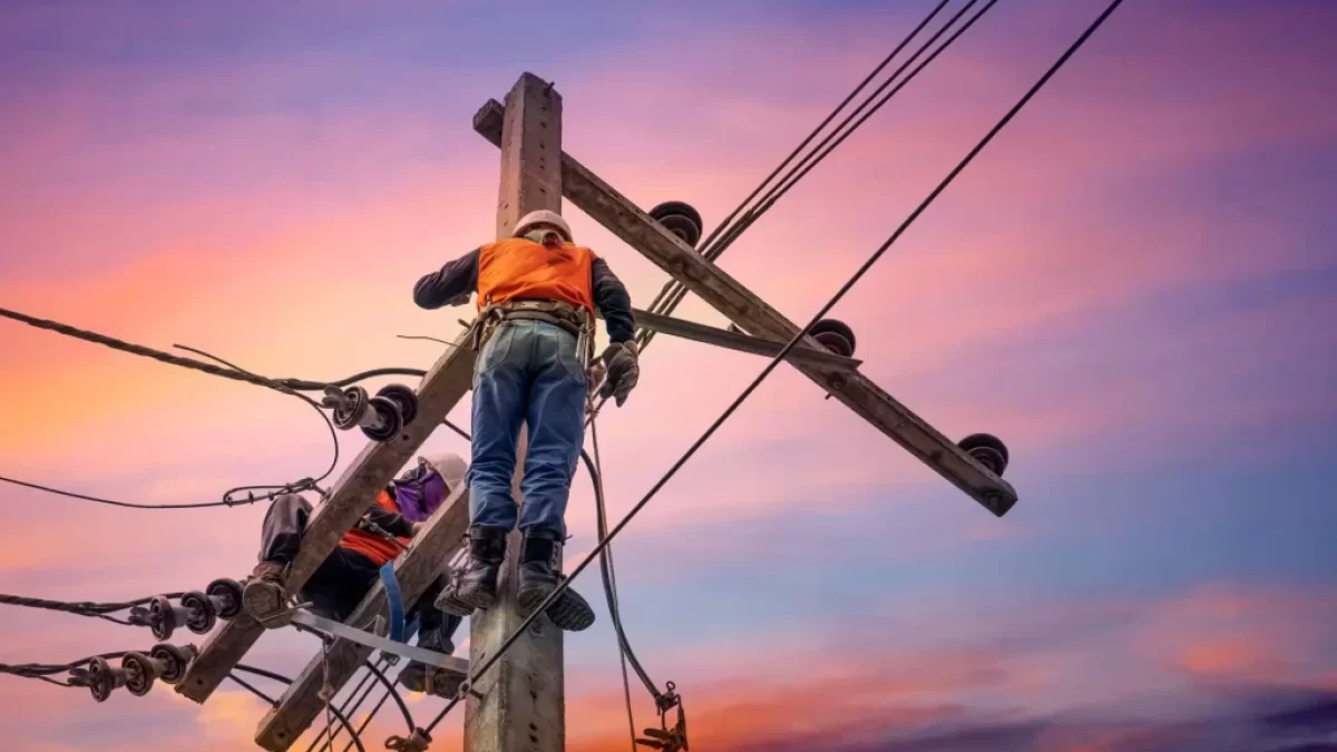 Elektrikář na sloupu vysokého vedení při západu slunce
