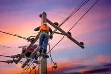 Elektrikář na sloupu vysokého vedení při západu slunce