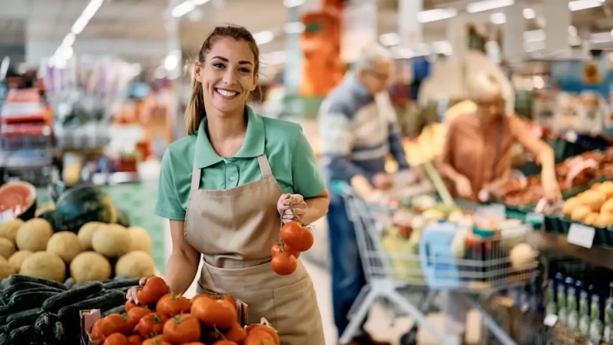 Prodavačka v supermarketu přerovnává rajčata.