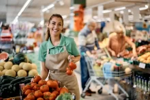 Prodavačka v supermarketu přerovnává rajčata.