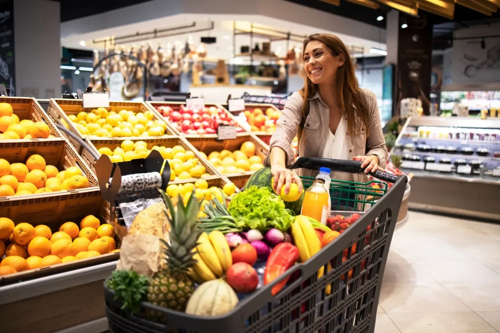 obchod2 1 - Techsvět Žena v supermarketu, si vybírá ovoce a její nákupní vozík je plný čerstvých potravin.