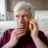 Starší muž, který drží mobilní telefon u ucha a vypadá znepokojeně.