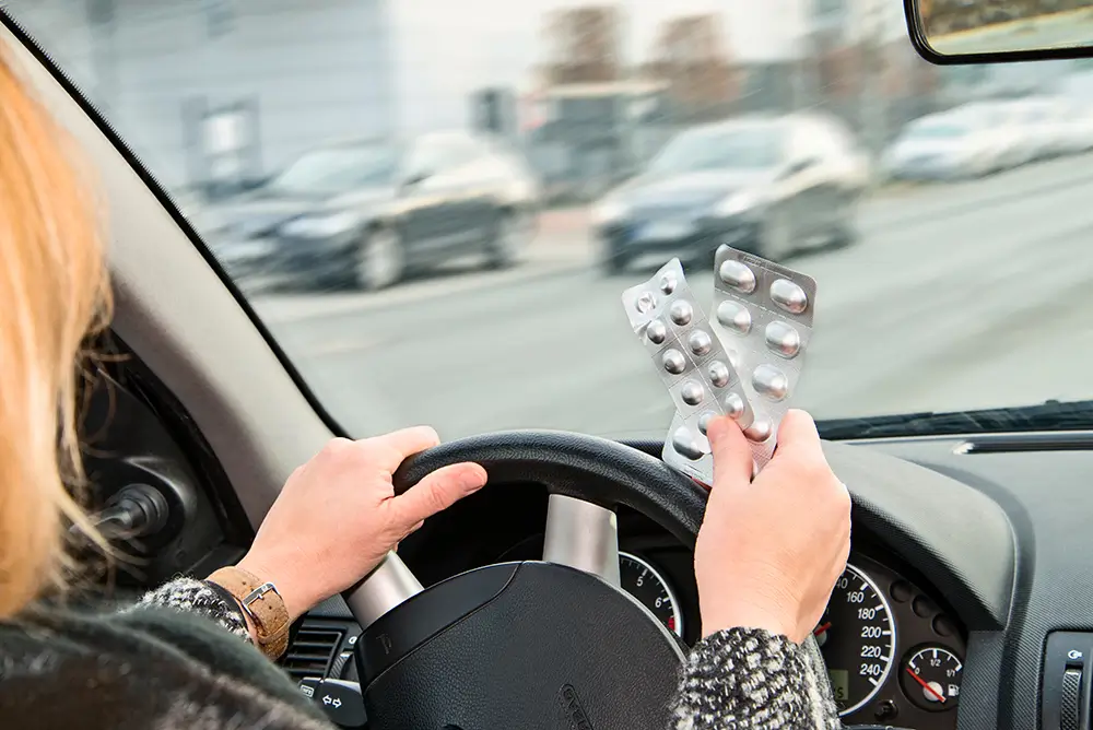 Nevhodné léky většinou nemají na krabičce žádné výrazné varování pro řidiče. - Techsvět žena drží léky v ruce při řízení automobilu