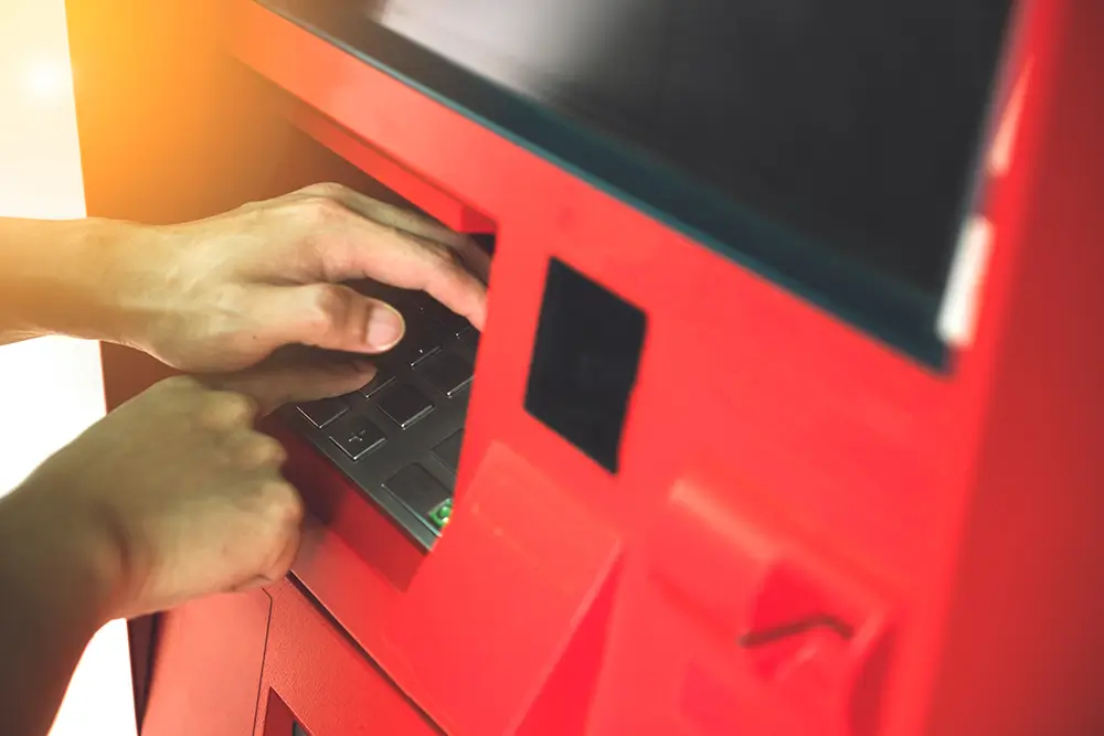 Při zadávání PIN zakrývejte volnou rukou klávesnici. - Techsvět muž zakrývá klávesnici v bankomatu