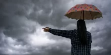 žena s deštníkem zírá na temné mraky