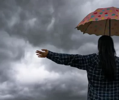 žena s deštníkem zírá na temné mraky