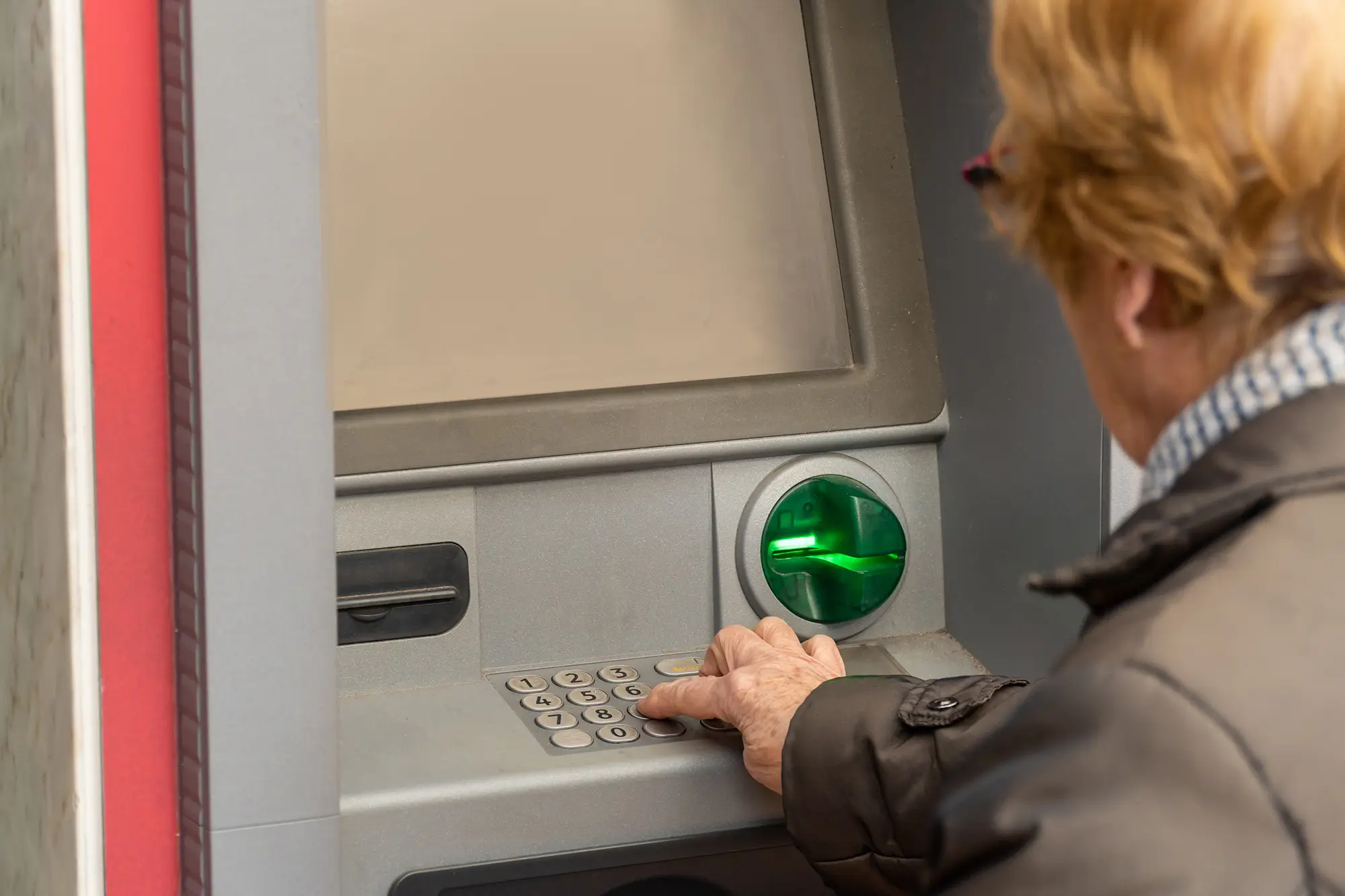 seniorka vybírá peníze z bankomatu