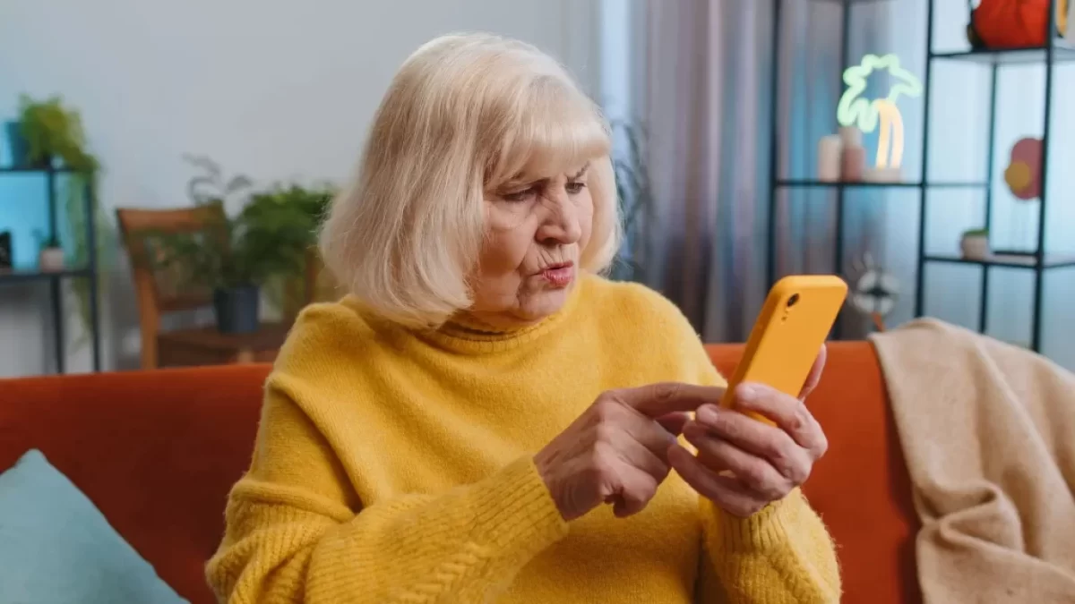 starší žena zmateně zírá na mobil