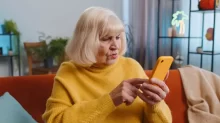 starší žena zmateně zírá na mobil