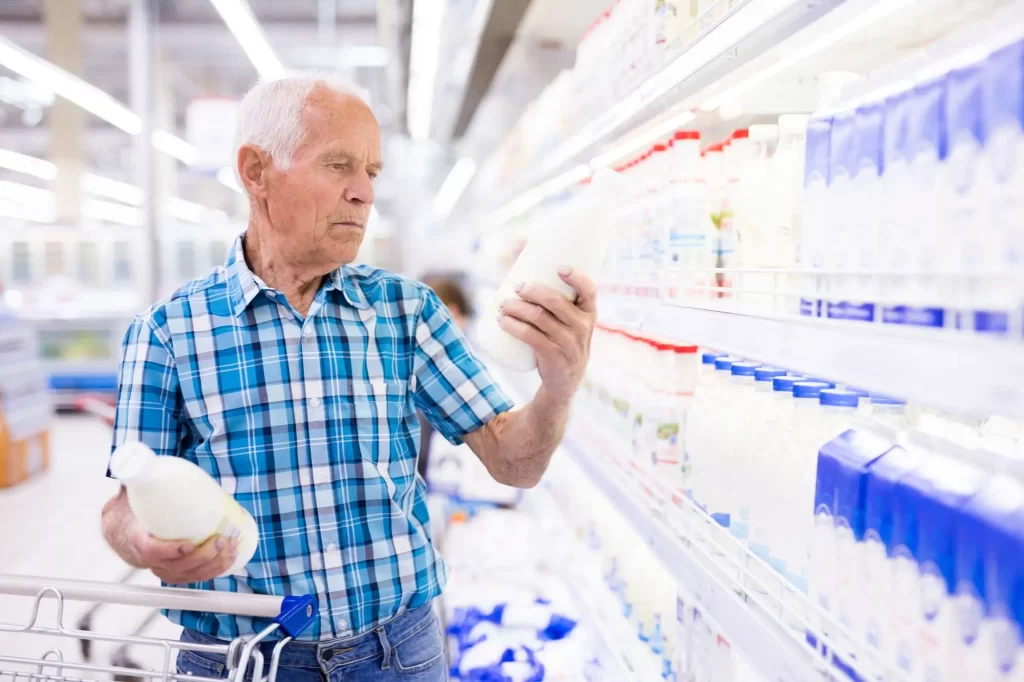 senior v supermarketu nakupuje mléko