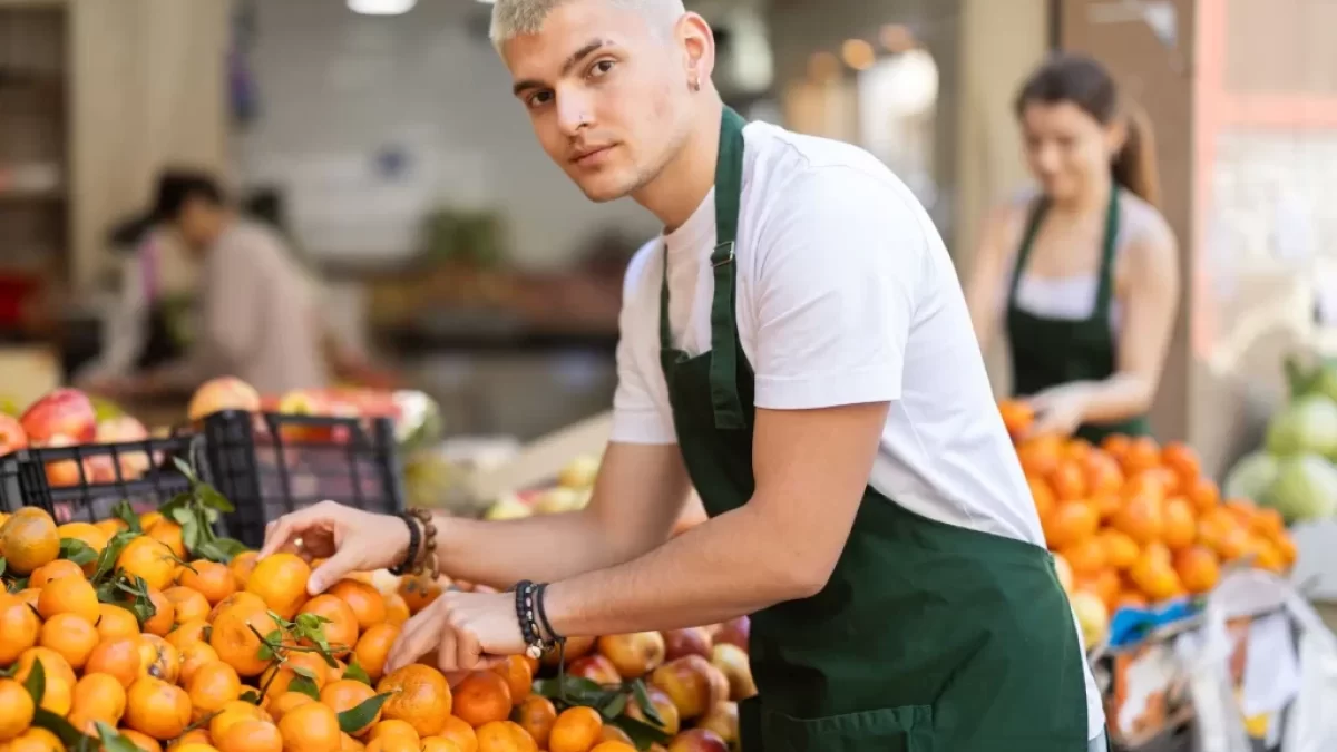 mladý prodavač v supermarketu doplňuje mandarinky