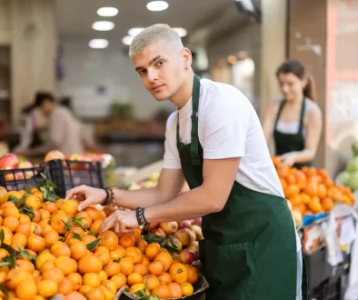 mladý prodavač v supermarketu doplňuje mandarinky