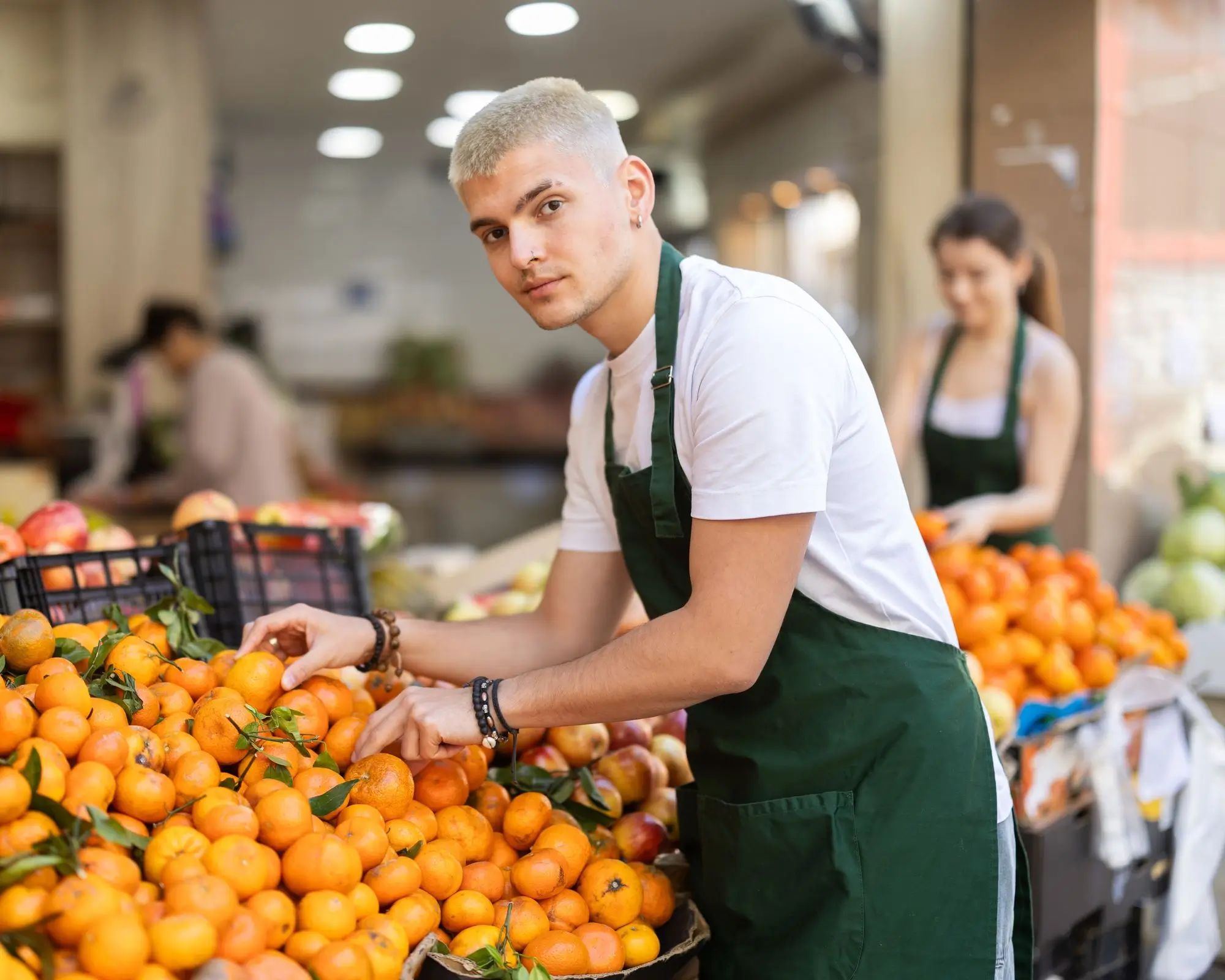 mladý prodavač v supermarketu doplňuje mandarinky