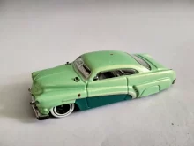 Detailní pohled na starožitný model osobního auta v pastelově zelené barvě.