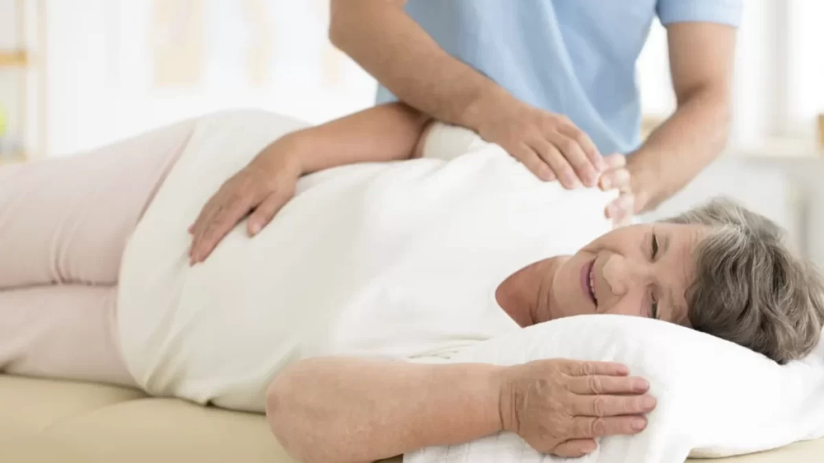 Starší žena se nechává na lehátku masírovat od zdravotní sestry