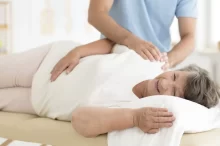 Starší žena se nechává na lehátku masírovat od zdravotní sestry