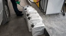 Muž na benzínce tankuje do několika plechových kanystrů