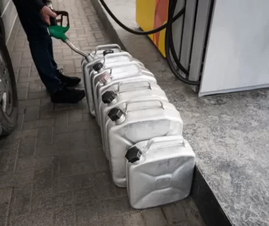 Muž na benzínce tankuje do několika plechových kanystrů