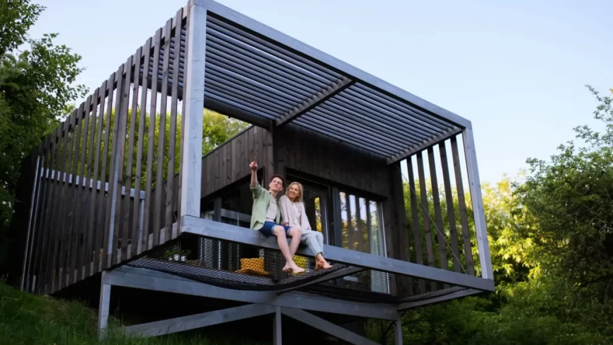 Moderní tiny house postavený na dřevěné konstrukci ve svahu, obklopený přírodou.