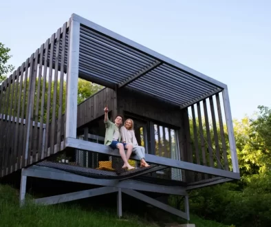 Moderní tiny house postavený na dřevěné konstrukci ve svahu, obklopený přírodou.