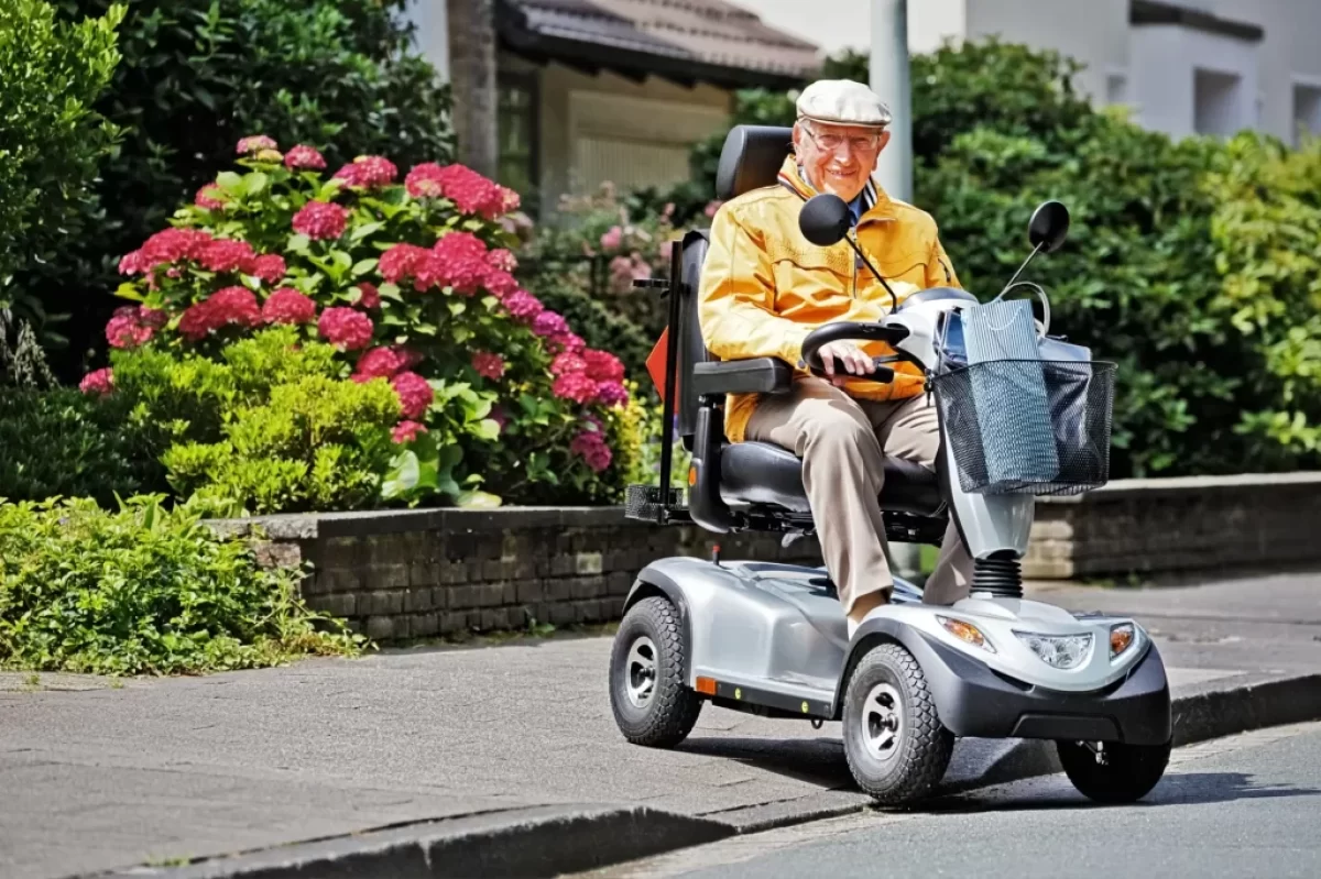 Starší muž sedí na elektrickém čtyřkolovém vozítku.