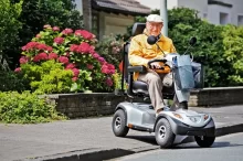 Starší muž sedí na elektrickém čtyřkolovém vozítku.