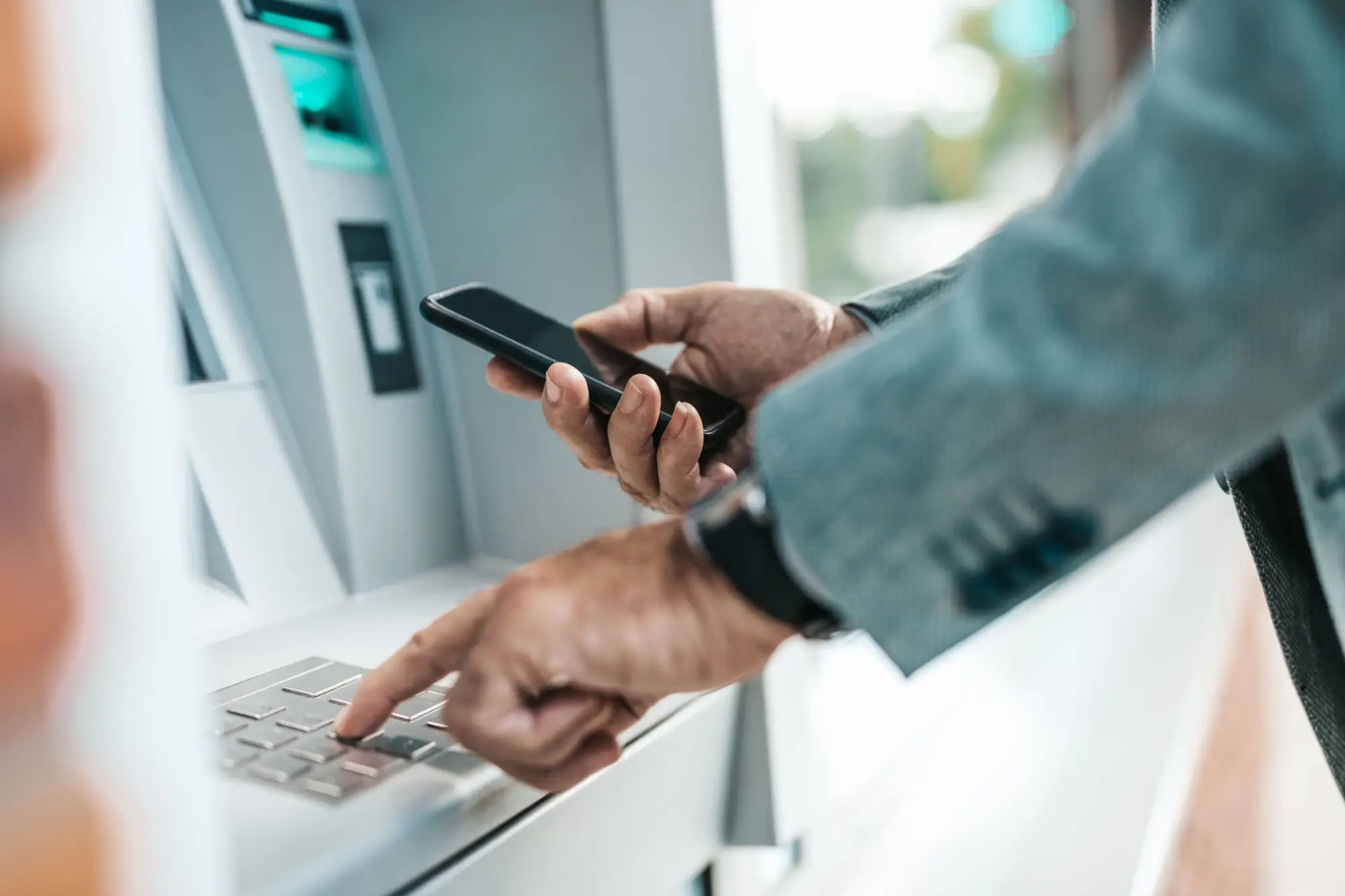 Shutterstock_1798966393 - Techsvět Muž vybírá z bankomatu za použití telefonu