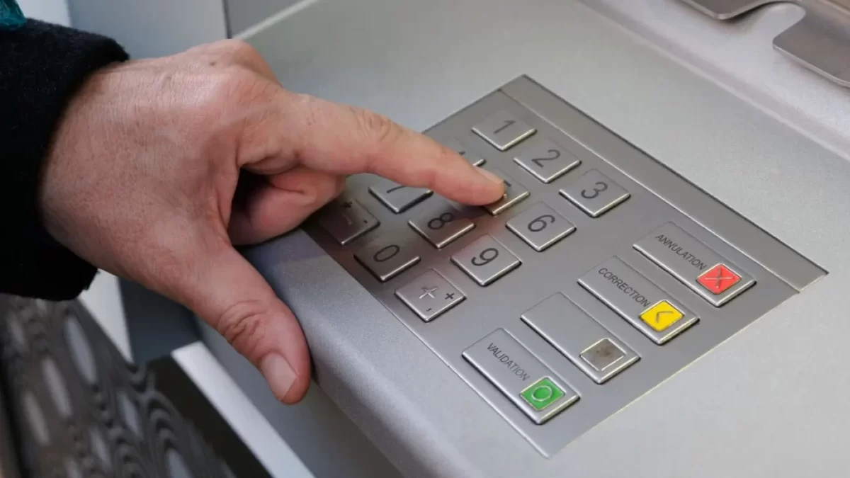 Muž zadává PIN u bankomatu
