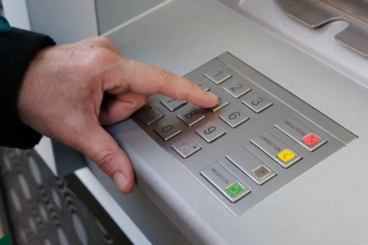 Muž zadává PIN u bankomatu